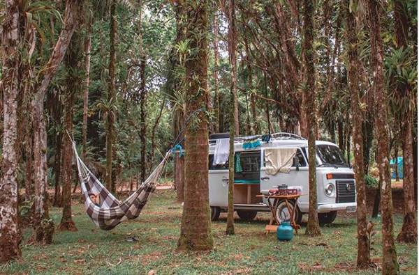 Kombi estacionada com uma rede do lado de fora para descansar 