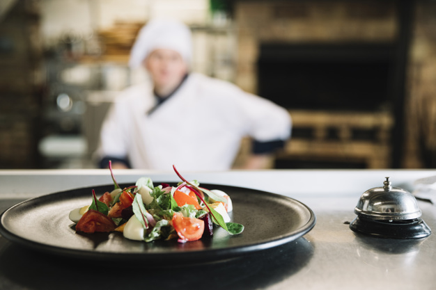 imagem de um prato de restaurante com o chef de cozinha atrás. 