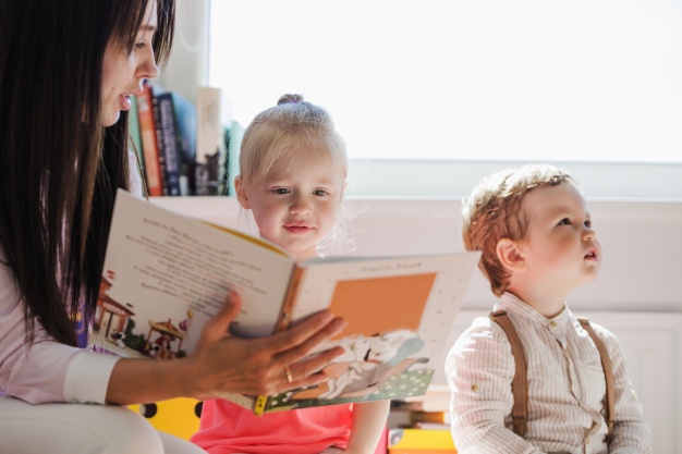 Babá lendo livro para as crianças durante seu intercâmbio