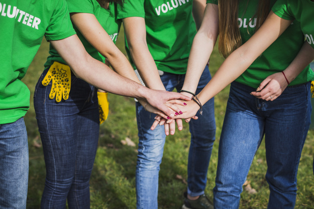 Vários voluntários intercâmbistas juntando as mãos.